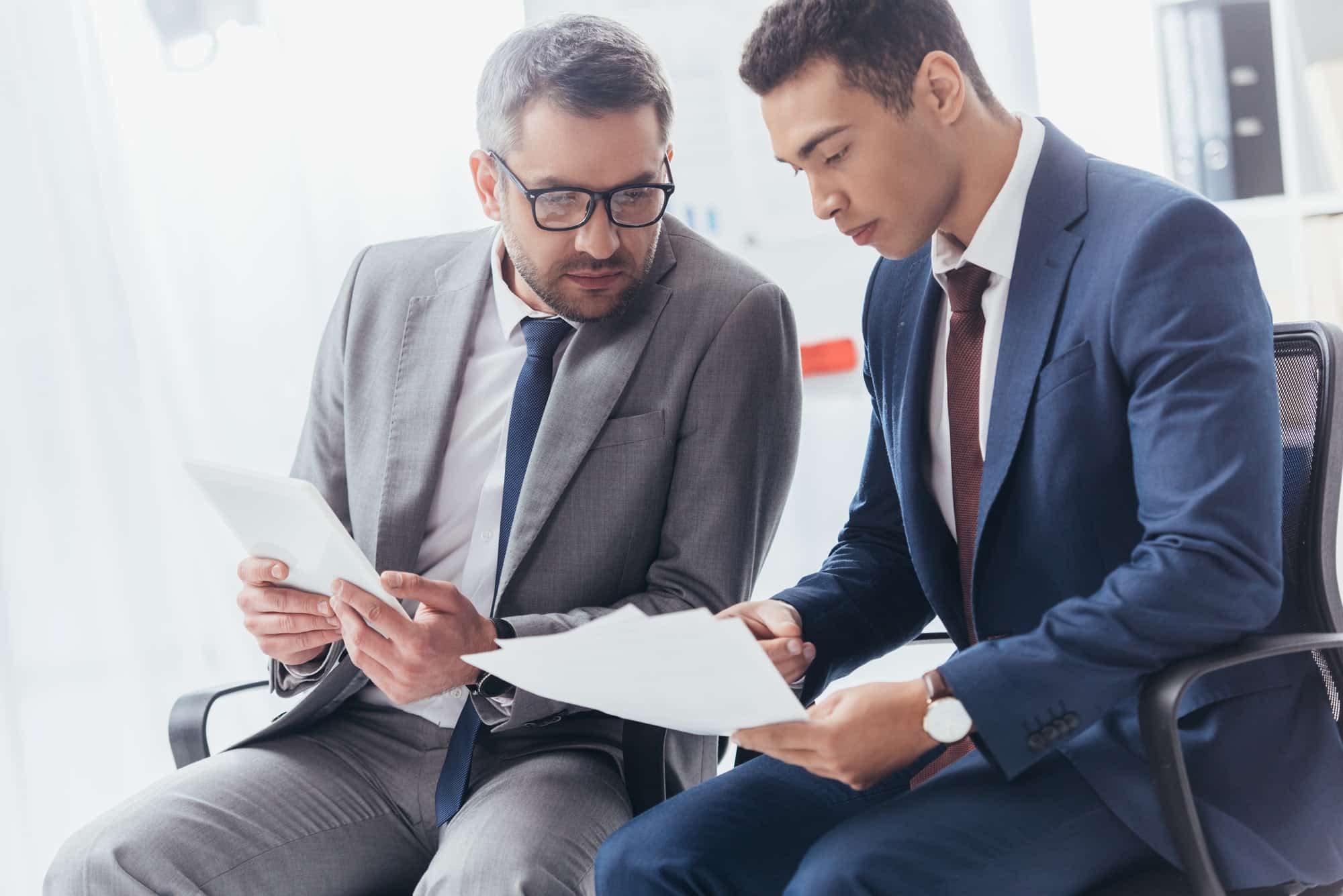 professional focused businessmen working with papers and digital tablet in office